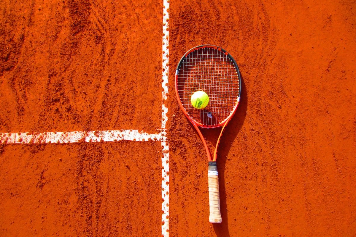 Tennis racket and Penn ball on red clay