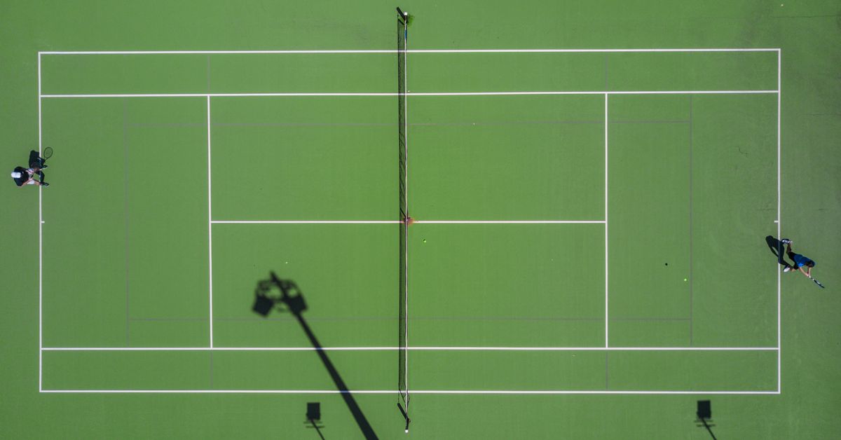 Two players with rackets on green hard court